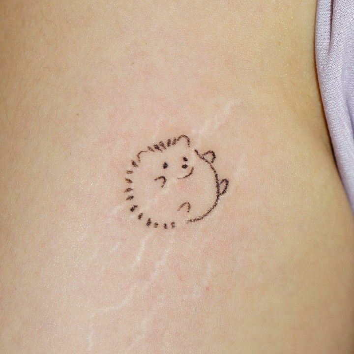 a small hedgehog tattoo on the back of a woman's stomach