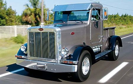 an old truck driving down the road with trees in the backgrounds