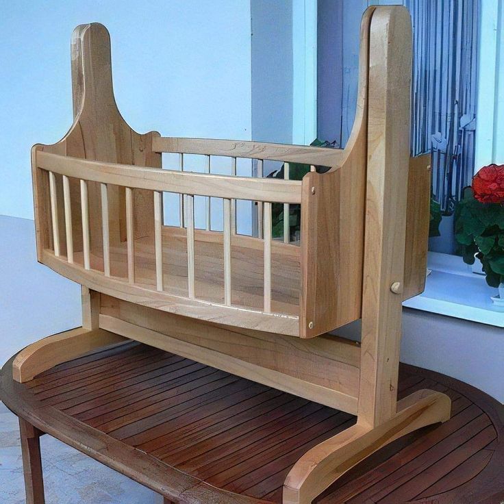 a wooden crib sitting on top of a table next to a potted plant