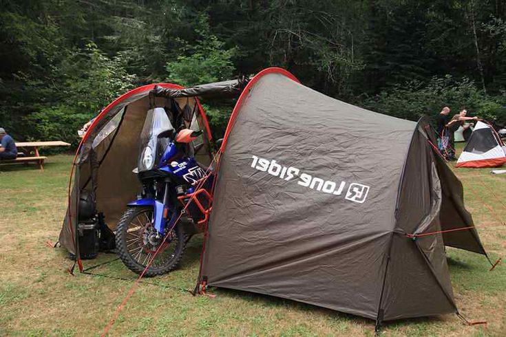 a tent set up in the middle of a field with two people sitting around it