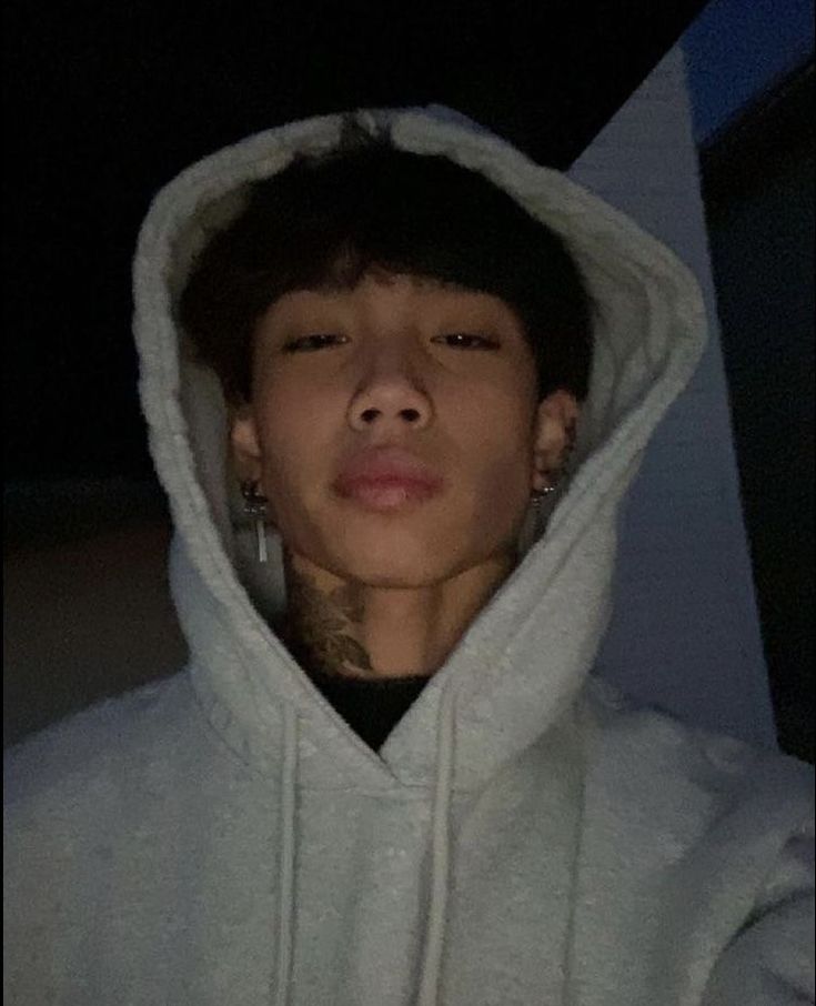 a young man in a white hoodie looking at the camera with his eyes closed