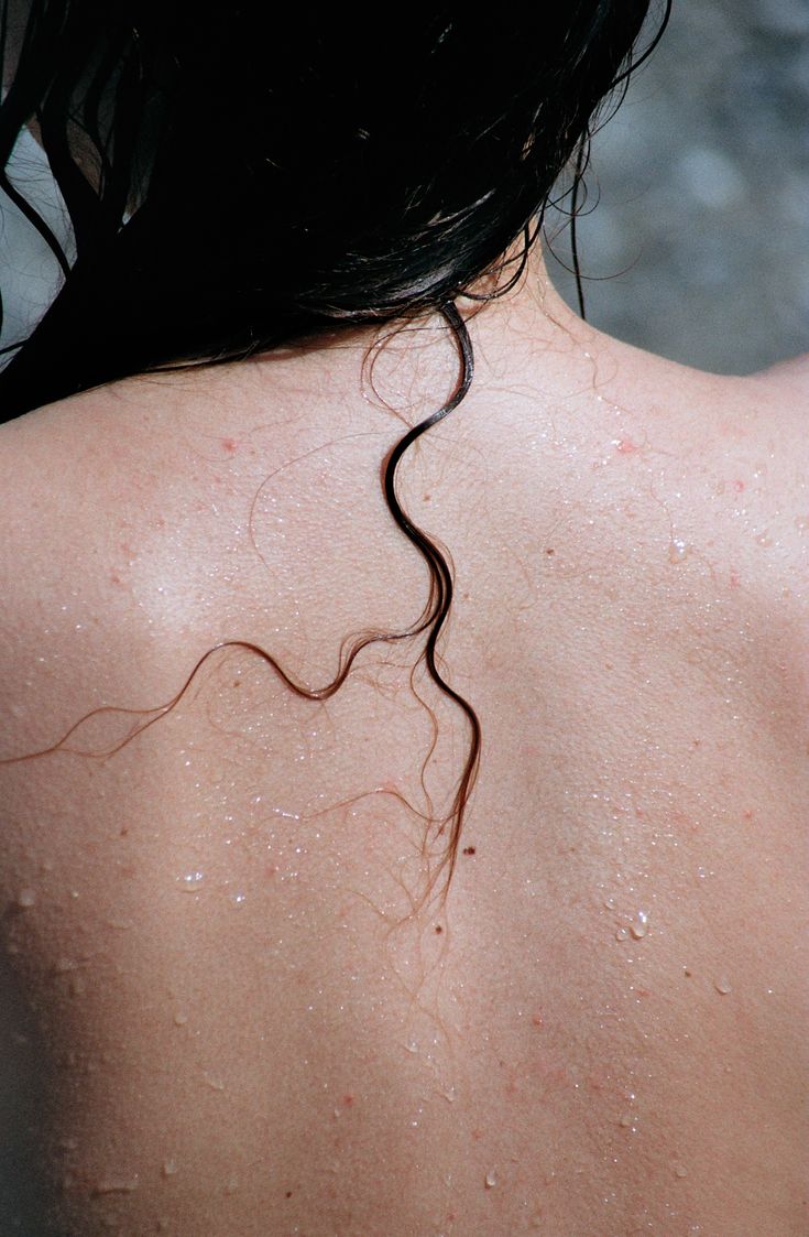 the back of a woman's head with hair flowing from her neck and shoulder