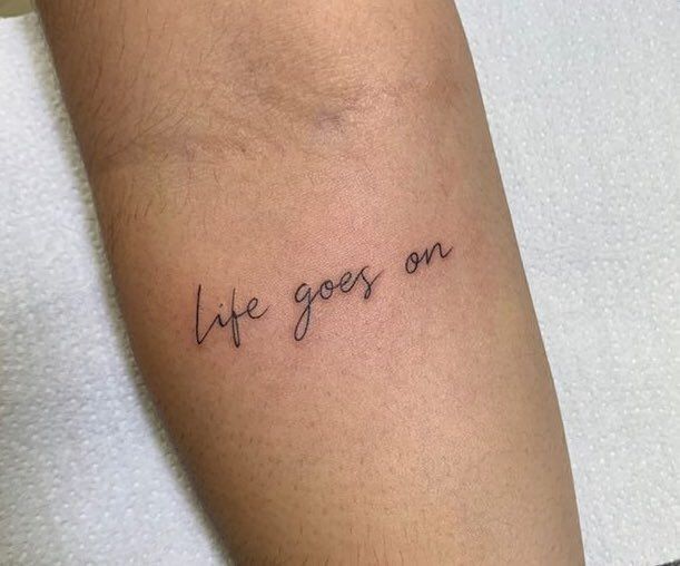 a person with a tattoo on their arm that says life goes on and the words are written in cursive font