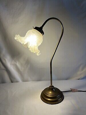 an antique brass desk lamp with a white glass shade on the base and a black cord