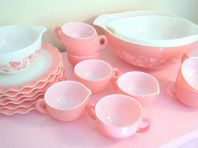 a pink table topped with dishes and cups