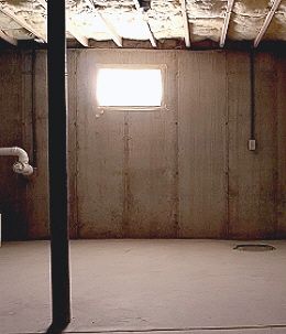 an unfinished room with exposed pipes and a window