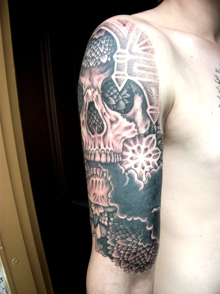 a man's arm with a skull and flowers tattoo on the left side of his body