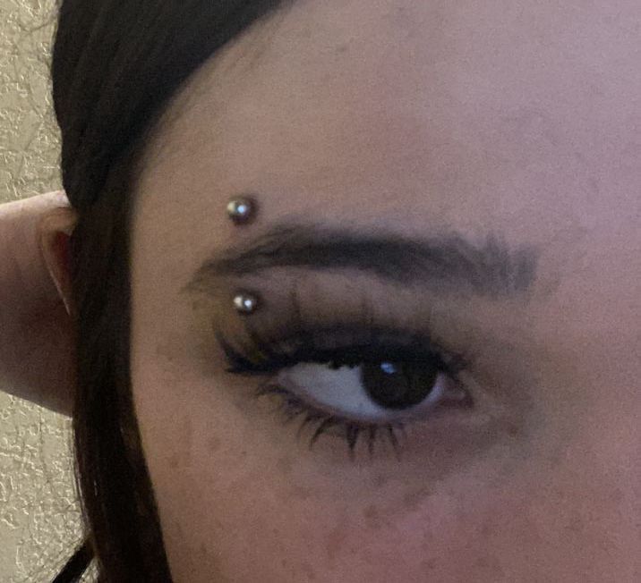 a woman with piercings on her eye looking at the camera