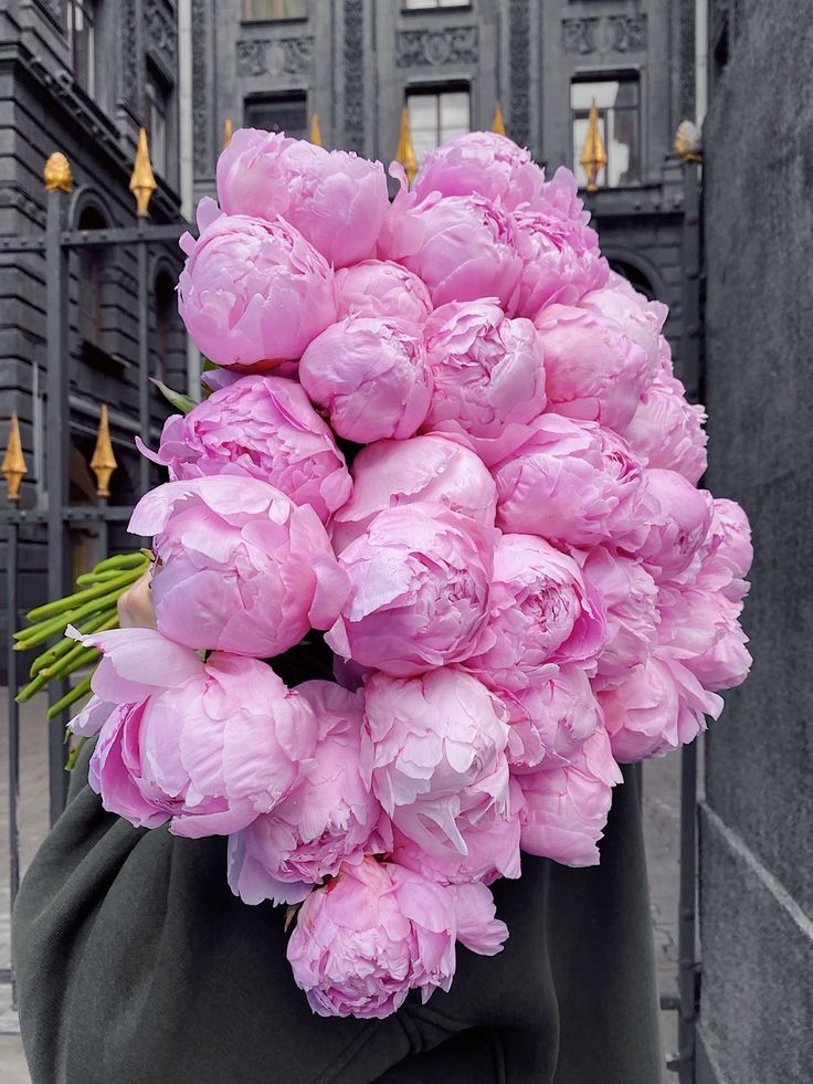 a person holding a large bouquet of pink flowers