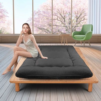 a woman sitting on top of a futon mattress