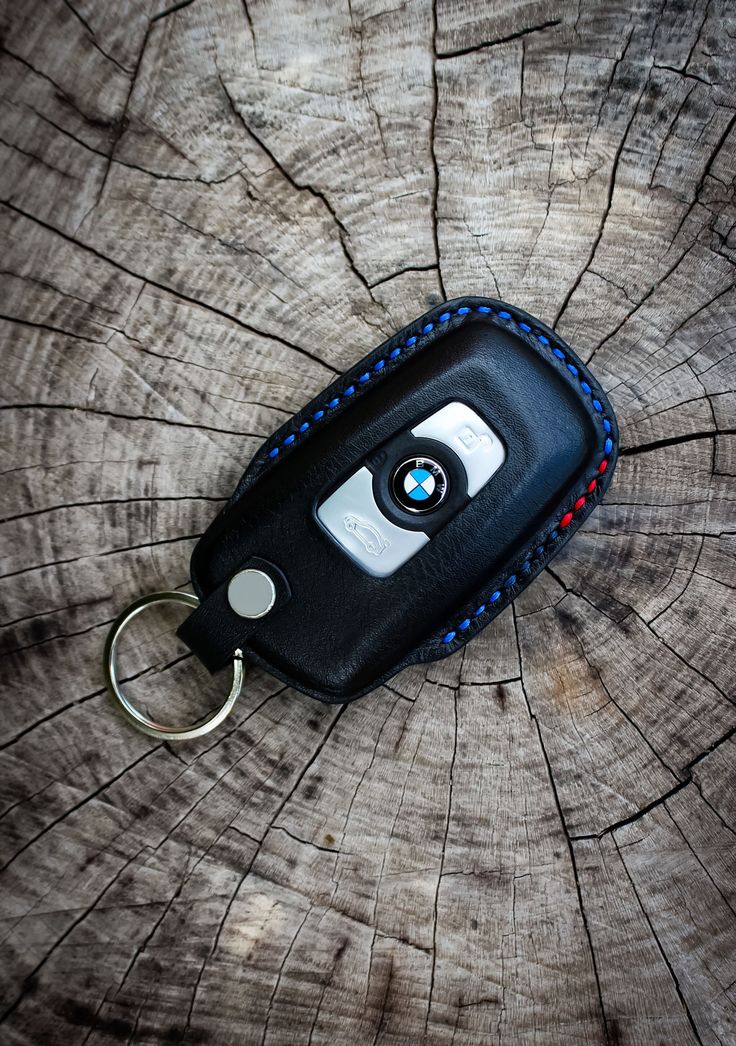 a bmw key fobring is on top of a tree trunk with blue stitching