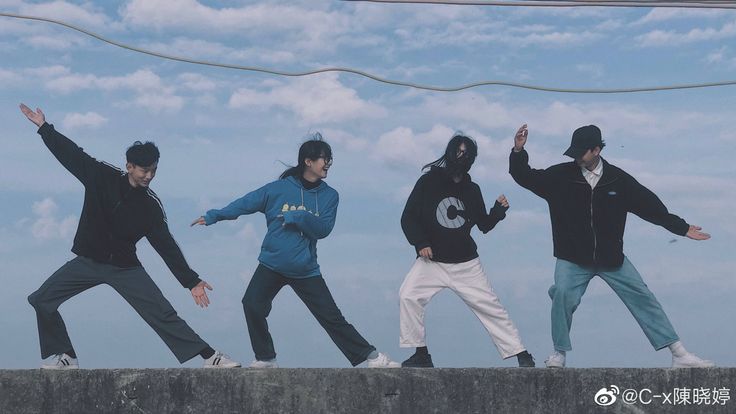 four young men jumping in the air with their hands up and one man holding his arms out