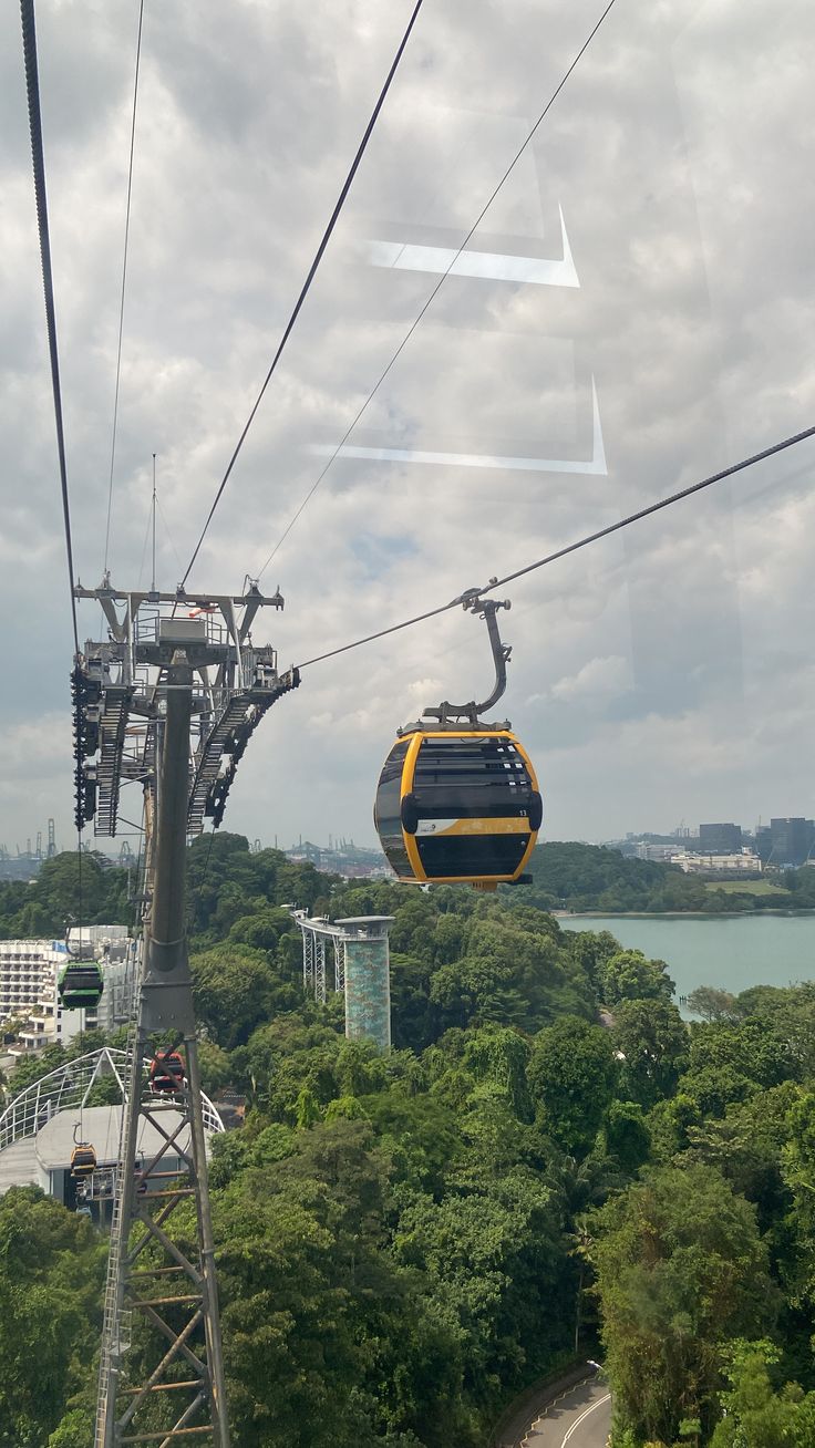 a yellow and black cable car going over trees