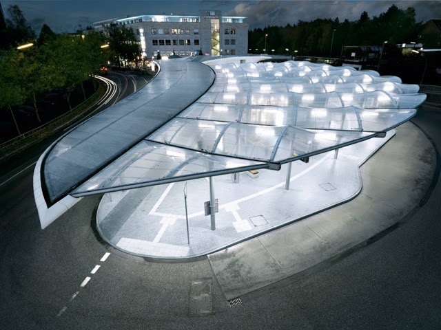 an aerial view of a parking lot at night with lights shining on the roof and walkway