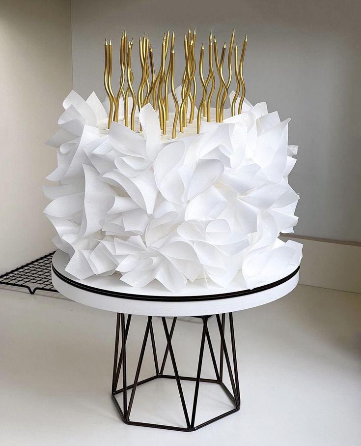 a cake made out of paper with gold forks on it's top, sitting on a table