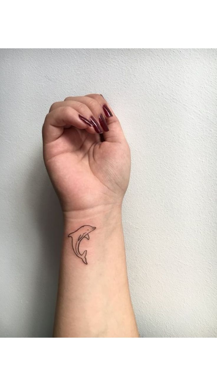 a woman's hand with a small tattoo on it, holding up her wrist