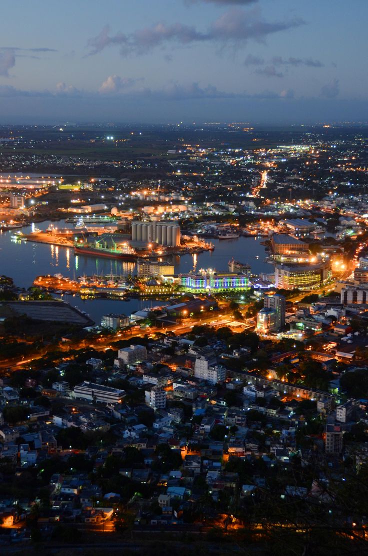 an aerial view of a city at night with lots of lights on the buildings and water