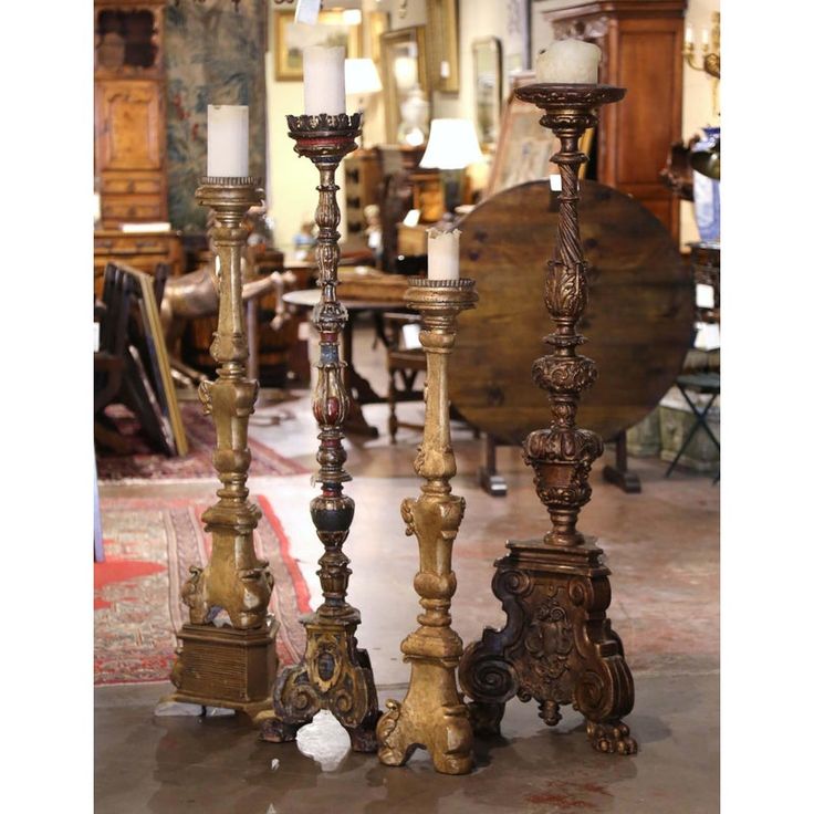 three tall candlesticks sitting next to each other in a room filled with furniture