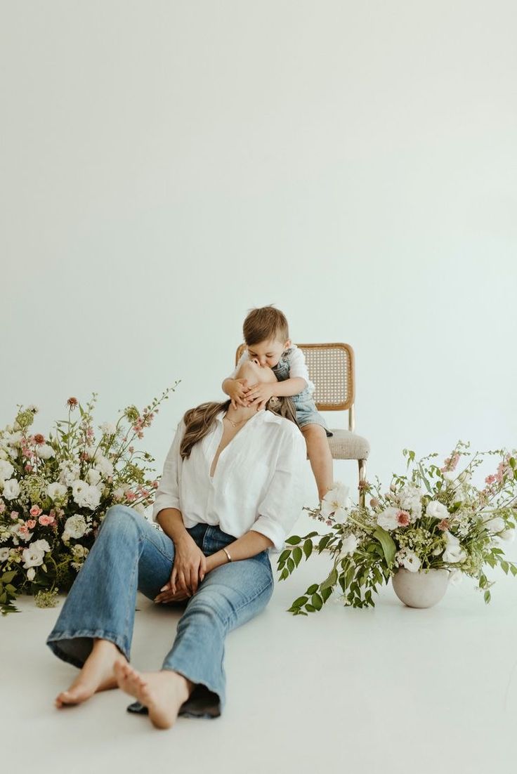 a woman sitting on the ground next to a man in jeans and a white shirt