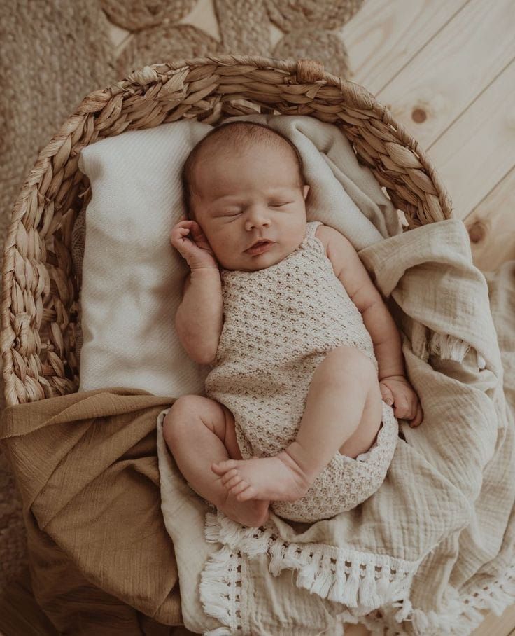 a baby is sleeping in a basket on the floor