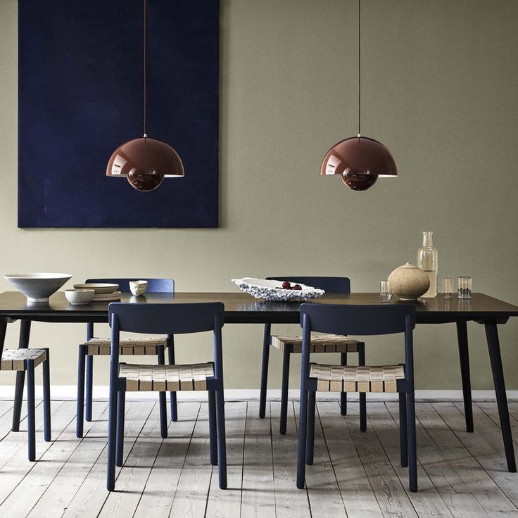 a dining room table with chairs and two pendant lights hanging from it's ceiling