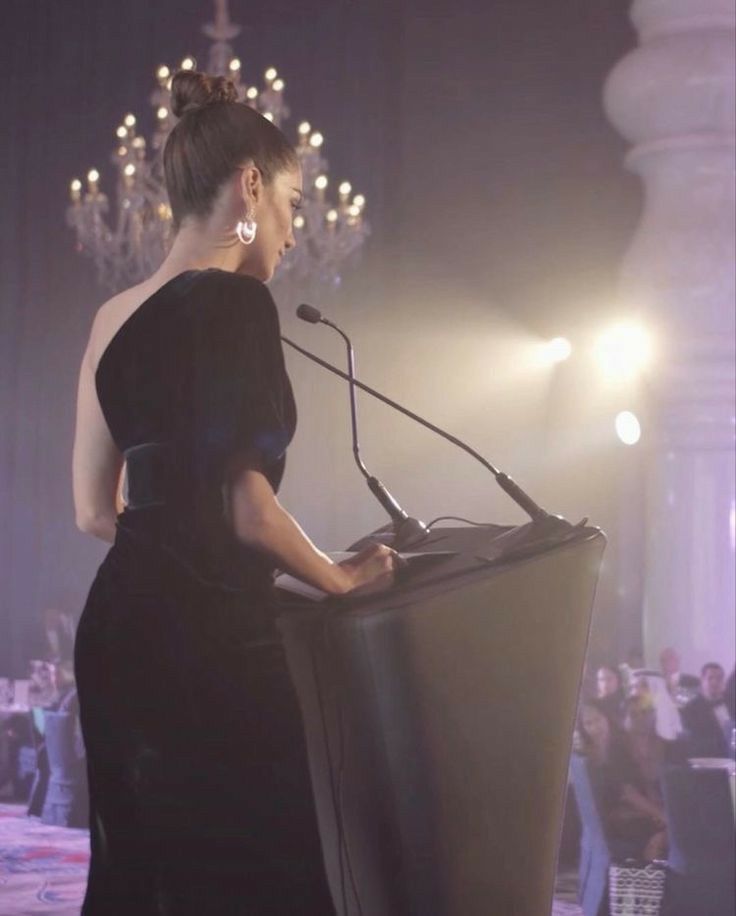 a woman in a black dress standing at a podium