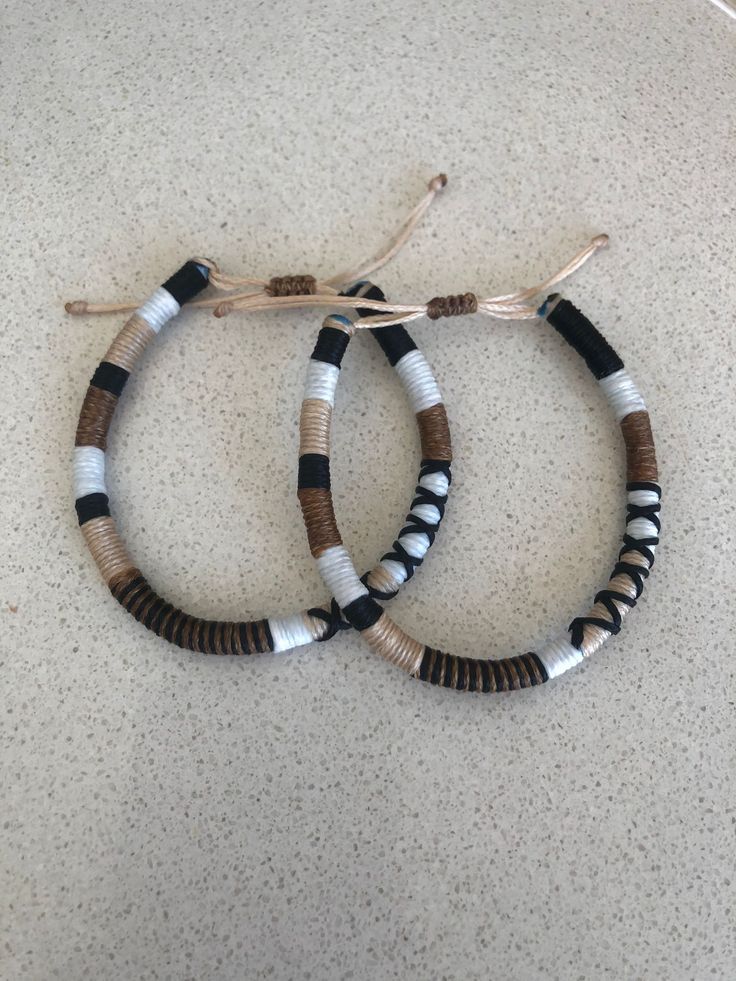 two bracelets with black, white and brown beads are on the floor next to each other