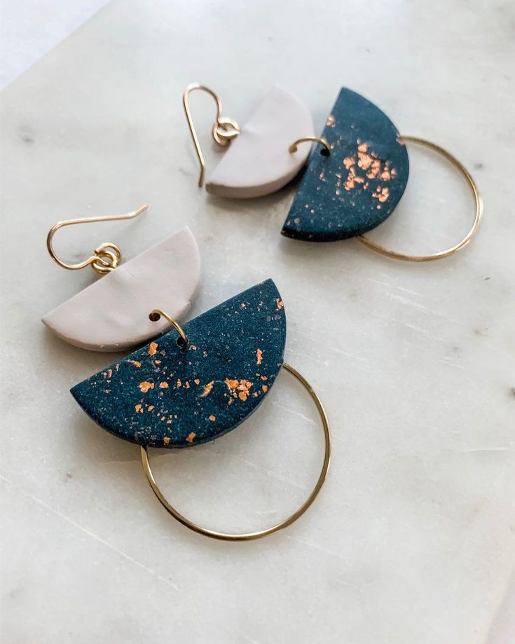 two pairs of blue and white earrings sitting on top of a marble counter with gold hoops