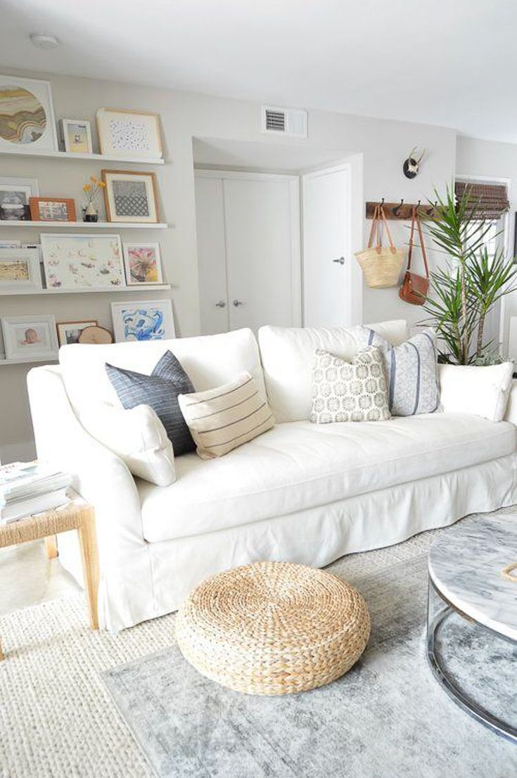 a living room with white couches and pictures on the wall above them, along with a round coffee table