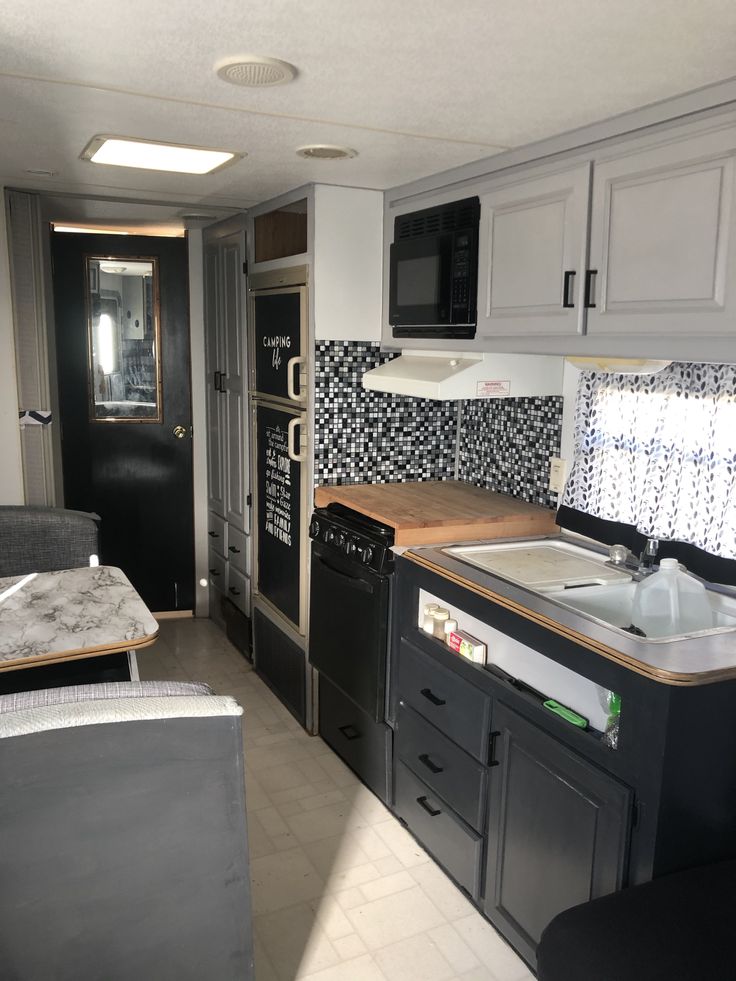 a kitchen with black and white tile on the backsplash, stove top oven, sink and microwave