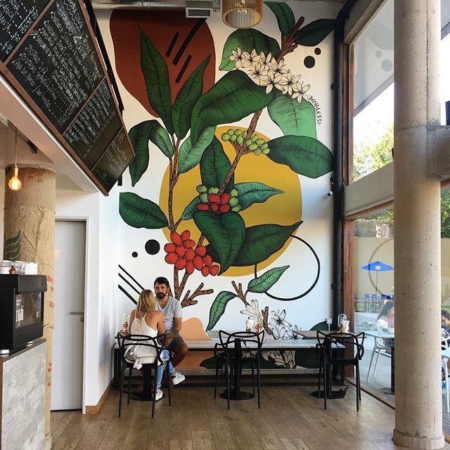 a man and woman sitting in front of a mural