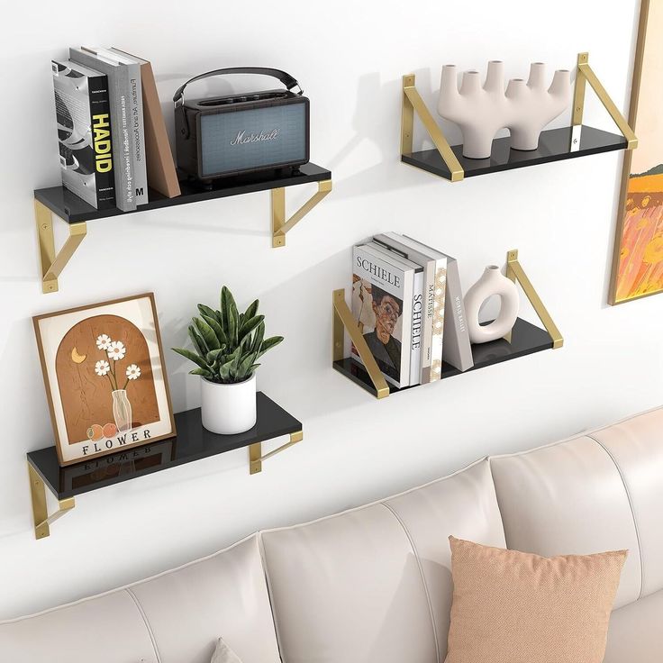 three shelves on the wall above a couch with books and other items in front of them