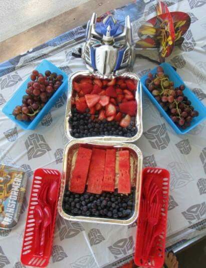 a table topped with trays filled with fruit and veggies on top of it