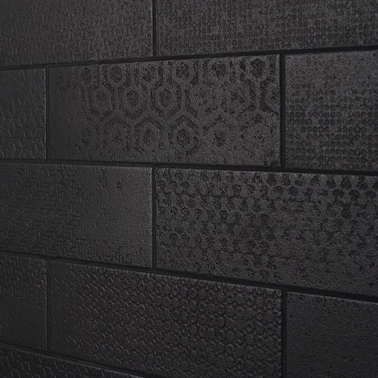 a black brick wall with white and gray tiles