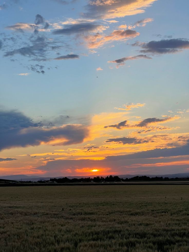 the sun is setting over an open field