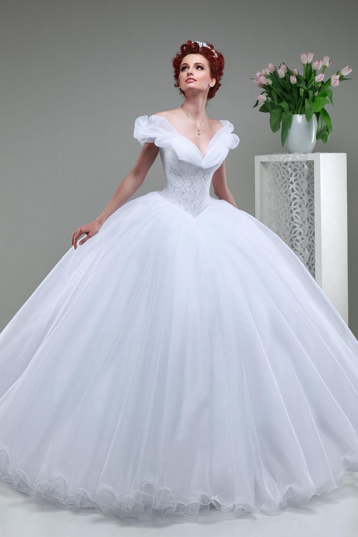 a woman in a white wedding dress standing next to a vase with flowers on it