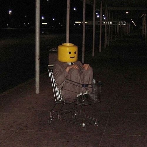 a person sitting in a shopping cart with a smiley face on it's head