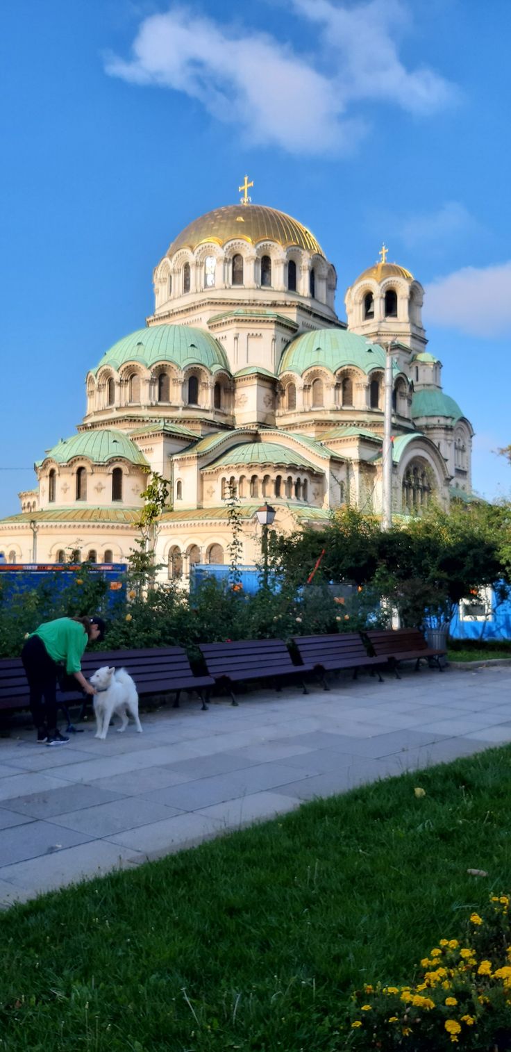 a woman walking her dog in front of a large building with domes on it's sides