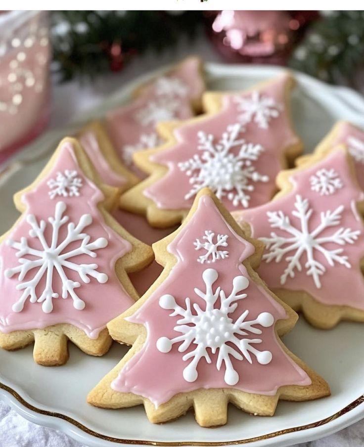 pink and white decorated christmas cookies with snowflakes on them sitting on a plate