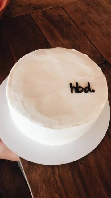 a person holding a cake with the word bd on it in front of them