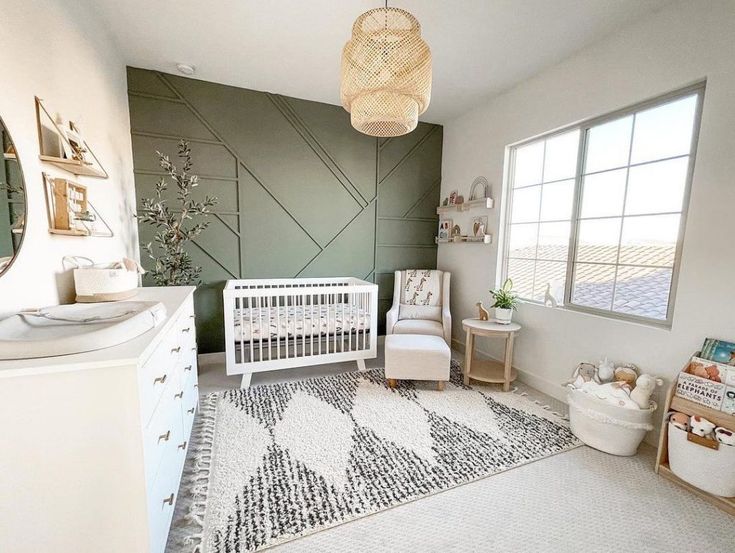 a baby's room with a white crib, dresser and chair in it