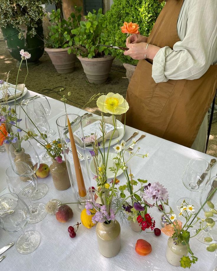 a table topped with lots of vases filled with different types of flowers and plants