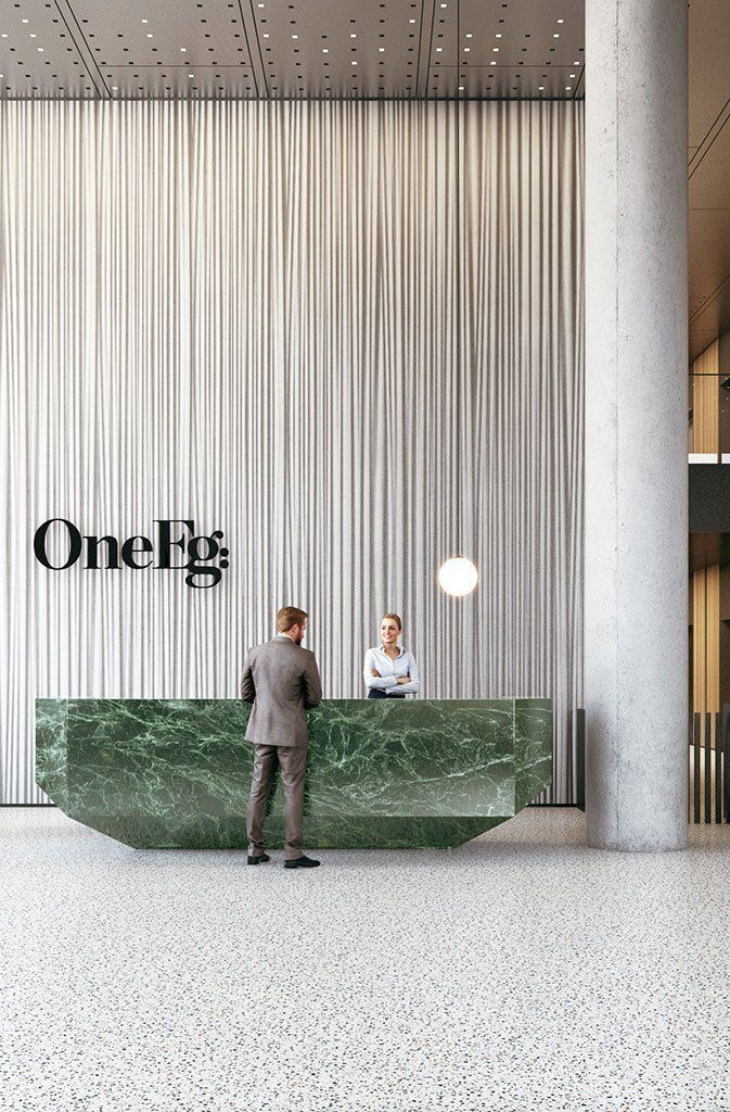 a man standing in front of a green marble reception desk with one big sign on the wall