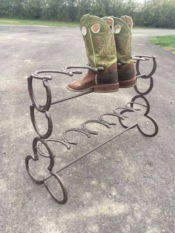 a pair of cowboy boots sitting on top of a metal stand with horseshoes in the shape of hearts