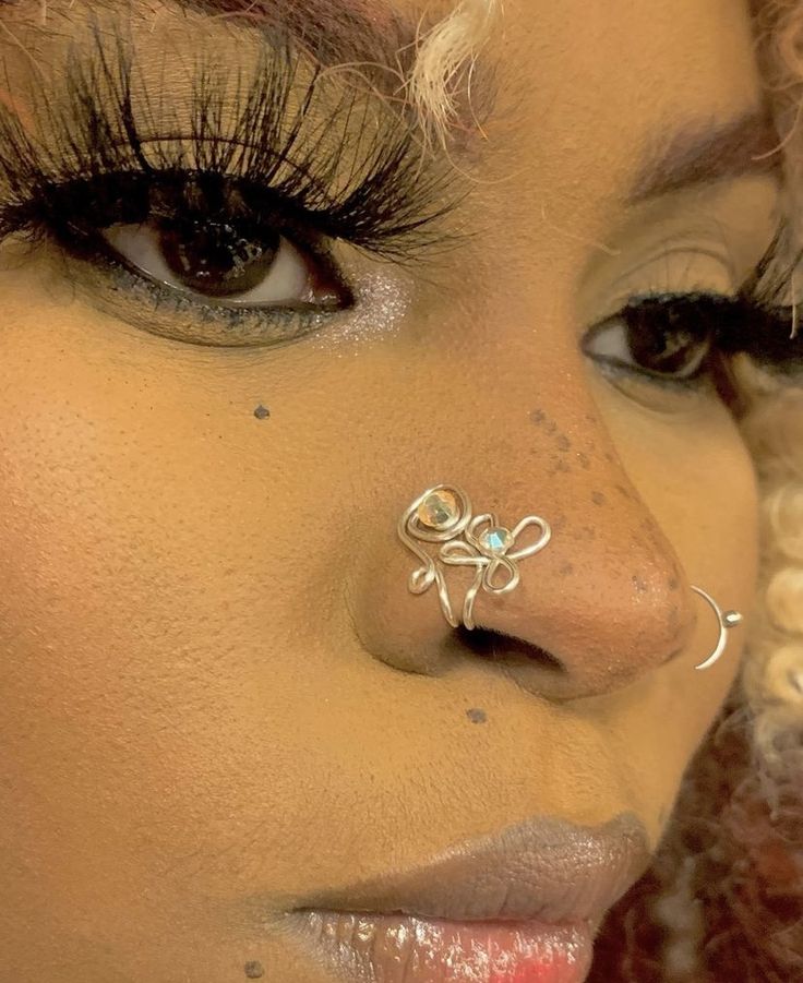 a close up of a woman with a nose ring and piercing on her nose, looking at the camera