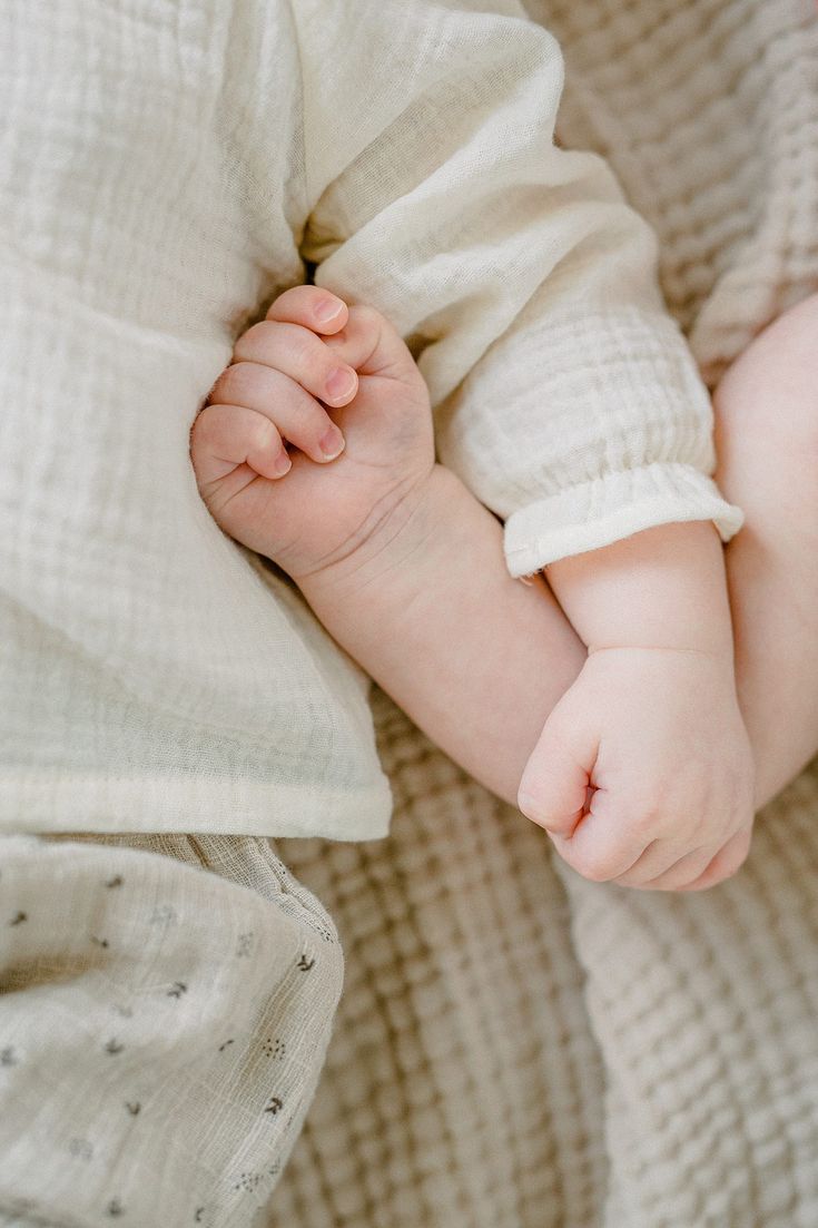 a baby laying on top of a white blanket