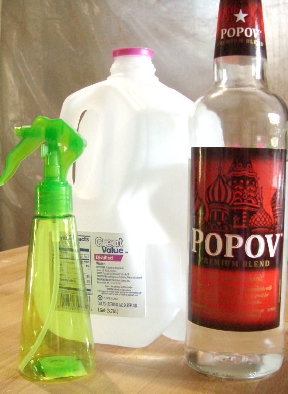 a bottle of popov next to a plastic jug with a green sprayer on it