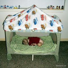 a small child laying on top of a bed with a tent over it's head