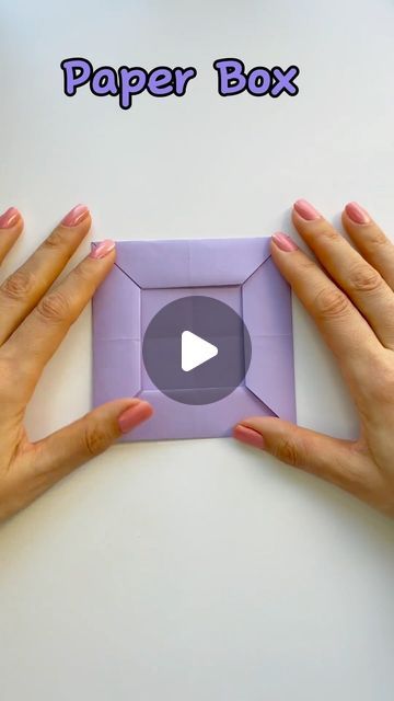 two hands holding an origami box with the words paper box in front of it