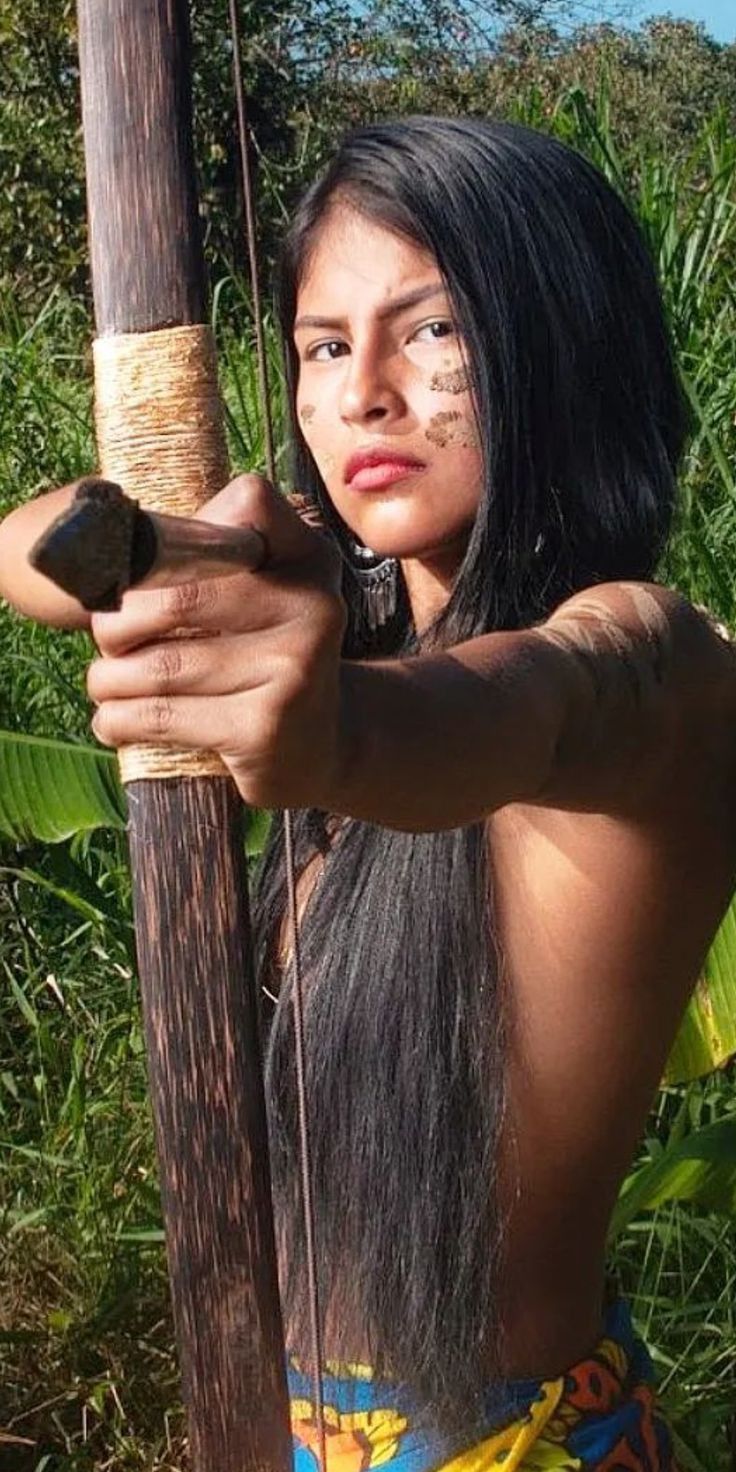 a young woman holding onto a pole in the jungle with her hand on it's shoulder